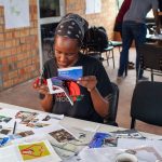 A student smiles as she carefully selects and cuts out images, adding her personal touch to the group's board
