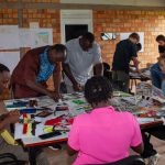 Team members collaborate closely, sorting through local fabrics and prints for their project