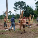 Teamwork in action as the main wooden frame of the pavilion is carried into place and assembled